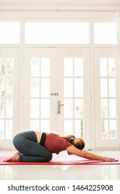 Young Woman Resting In Child’s Pose On Yoga Mat After Exercising At Home