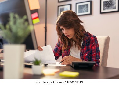 Young Woman Reviewing Documents, Working Late In A Home Office