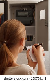 Young woman rewrites the electrical meter readings at home in Russia - Shutterstock ID 150758141