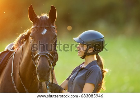Young woman rider with her horse in evening sunset light. Outdoor photography in lifestyle mood