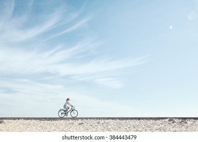 Young woman riding bicycle with basket against blue sky during summer - healthy lifestyle concept - Powered by Shutterstock