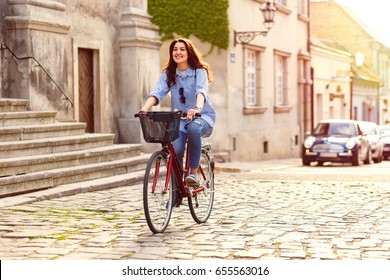 Young woman riding a bicycle down the street at sunset.
