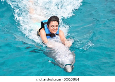 Young Woman Riding Dolphin Holding His Fin