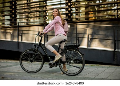 Young woman riding e bike in urban enviroment at sunny day - Powered by Shutterstock