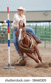 Young Woman Riding A Horse In A Pole Bending Race At A Rodeo.