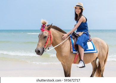 Young Woman riding horse in sand beach