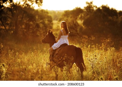 Young Woman Riding A Horse At Sunset