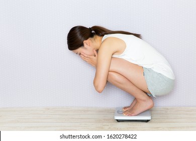 Young Woman Riding A Weight Scale.