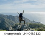 Young woman right on top of mountain in Garrapata state park- Big Sur, hiking trail completed, She has her arms open as a sign of gratitude for life.