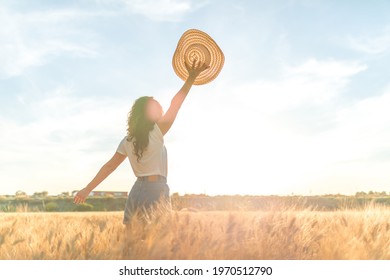 Young woman in a ripe wheat field celebrating with a hat in hand in a sunny wheat field. Concept of prosperity and warmth. - Shutterstock ID 1970512790