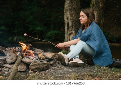 Young Woman Roasting Marshmallows Over A Campfire