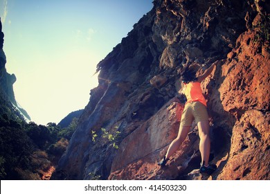 young woman rock climber climbing at mountain cliff - Shutterstock ID 414503230