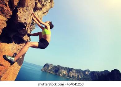 Young Woman Rock Climber Climbing At Seaside Mountain Cliff