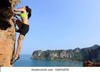 young woman rock climber climbing at seaside cliff - Powered by Shutterstock