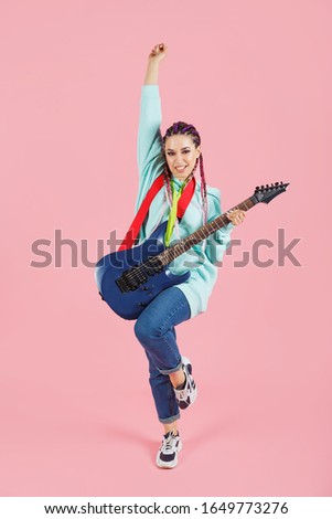 Young woman rock musician with amp isolated on pink