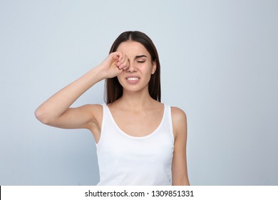 Young Woman Rubbing Eye On Light Background. Annoying Itch