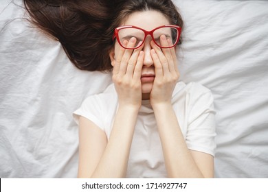 Young woman rubs her eyes after using glasses. Eye pain concept, poor vision.