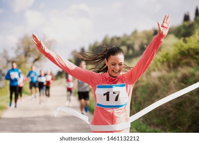 Young woman runner crossing finish line in a race competition in nature. - Shutterstock ID 1461132212