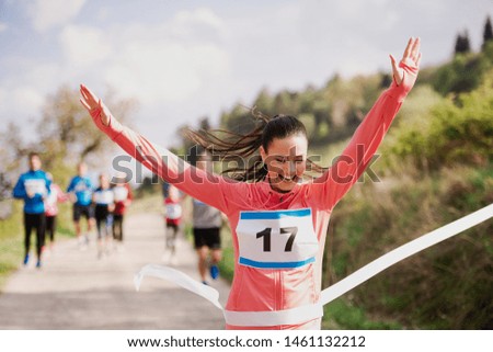 Young woman runner crossing finish line in a race competition in nature.