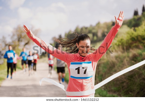 Young woman runner crossing finish line in a race\
competition in nature.