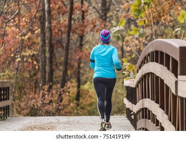 Young Woman Runner On A Bridge Leading To The Wooden Trail; Fall In Missouri, Midwest