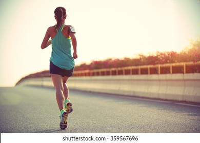 young woman runner running on city bridge road - Shutterstock ID 359567696