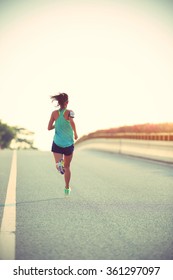 young woman runner running on city bridge road - Shutterstock ID 361297097