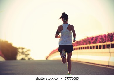 young woman runner running on city bridge road - Shutterstock ID 457776085
