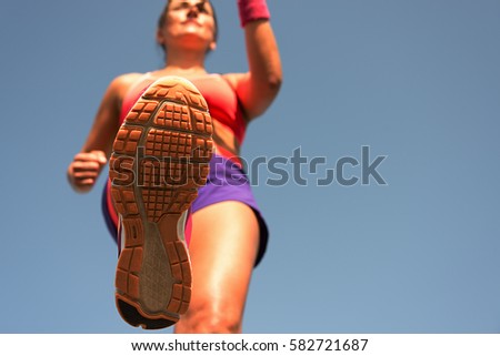 Young woman runner running,training for marathon run.View from below
