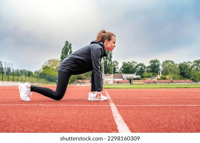 Young woman runner in start position on running track while work out. - Powered by Shutterstock