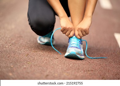 young woman runner tying shoelaces  