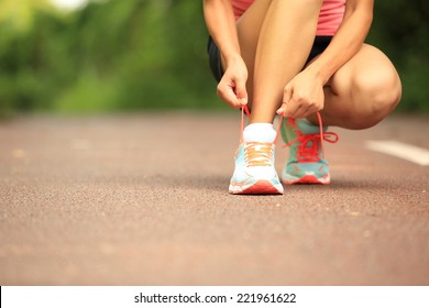 Young woman runner tying shoelaces  - Powered by Shutterstock