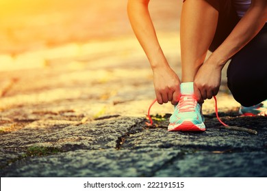 young woman runner tying shoelaces 