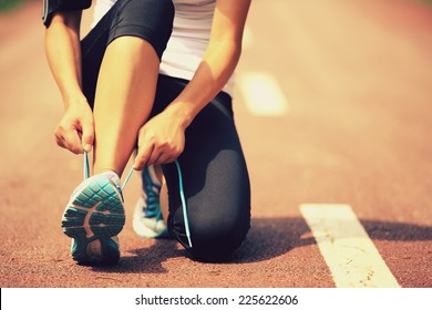 young woman runner tying shoelaces 