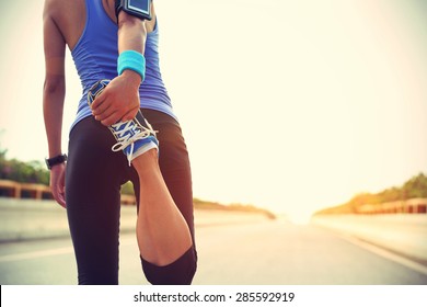 young woman runner warming up before run on city 