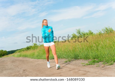 young woman running along a rural road, exercise outdoors