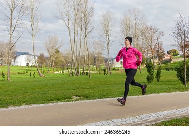 Young Woman Running On A Cold Winter Day In An Urban Park.