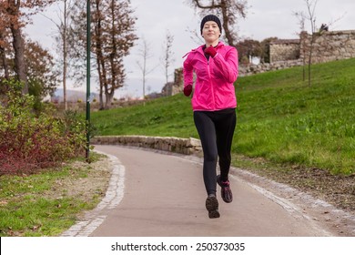 Young Woman Running On A Cold Winter Day In An Urban Park.