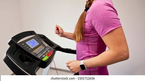 The Young Woman Is Running On Her Treadmill In Home