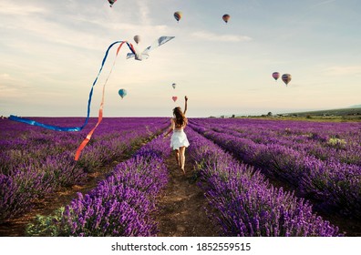 young woman running on lavender field with kite, freedom concept
