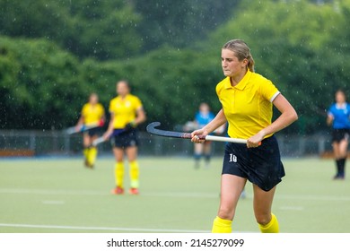 Young woman running on the pitch during the field hockey game in rain