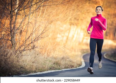 Young Woman Running Outdoors In A City Park On A Cold Fall/winter Day