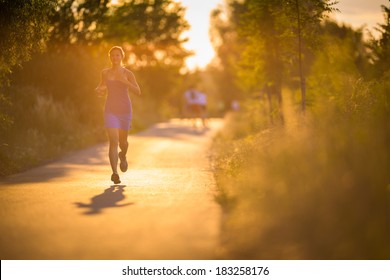 Young woman running outdoors on a lovely sunny summer evening (shallow DOF; color toned image)