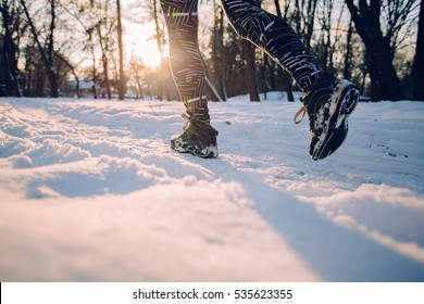 Young Woman Running Outdoors  At Snowly Winter Under Sunlight.