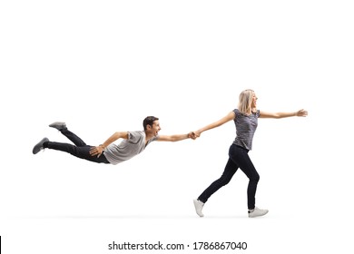 Young Woman Running And Pulling A Young Man By The Hand Who Is Floating In Air Isolated On White Background