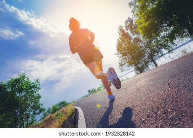 Young woman running sprinting on road. Fit runner fitness runner during outdoor workout with sunset background.