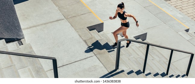 Young woman running up the steps as exercise routine. Athlete in sportswear exercising on stairs outdoors. - Powered by Shutterstock