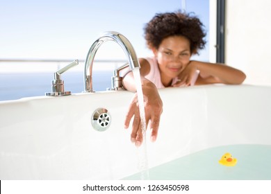 Young Woman Running Water For Bath At Home