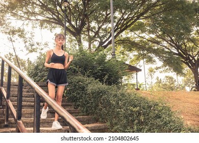 A Young Woman Runs Down A Flights Of Steps At A Downhill Slope. Outdoor Exercise Scene.