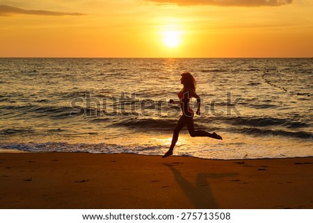 The young woman runs on a beach at sunset